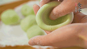 將均分的艾草面團(tuán)搓成圓，挖一個(gè)窩，放入餡心，再搓成圓。