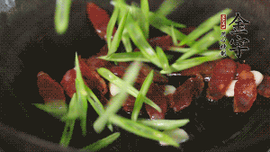 先后下香腸片、四季豆絲均勻翻炒，加適量清水燜煮一下。