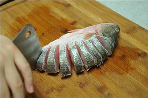 將鱸魚清洗干凈，從脊椎處切斷至腹部，腹部保留1cm左右不要切斷。