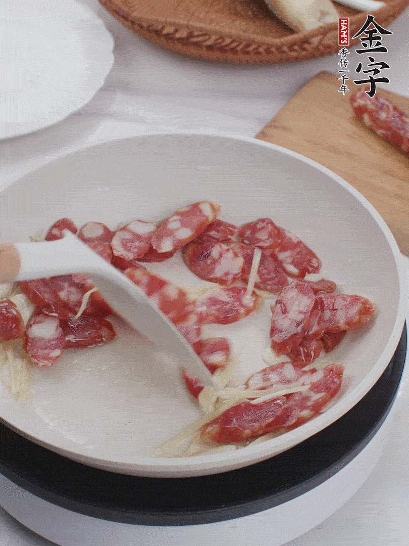 油溫3成熱時(shí)，下姜絲、蒜片、香腸炒出油脂。