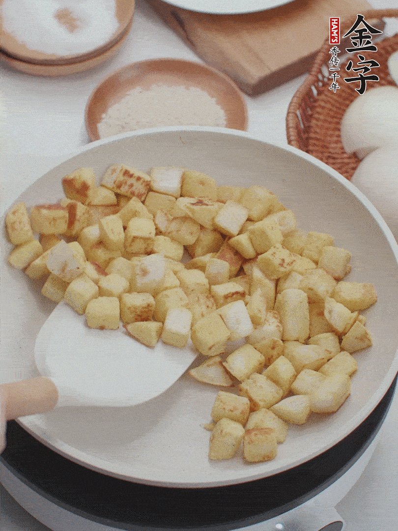 起鍋熱油，倒入饅頭丁，小火煎至蛋液凝固定型再翻面，饅頭丁部煎至金黃時(shí)盛起待用。