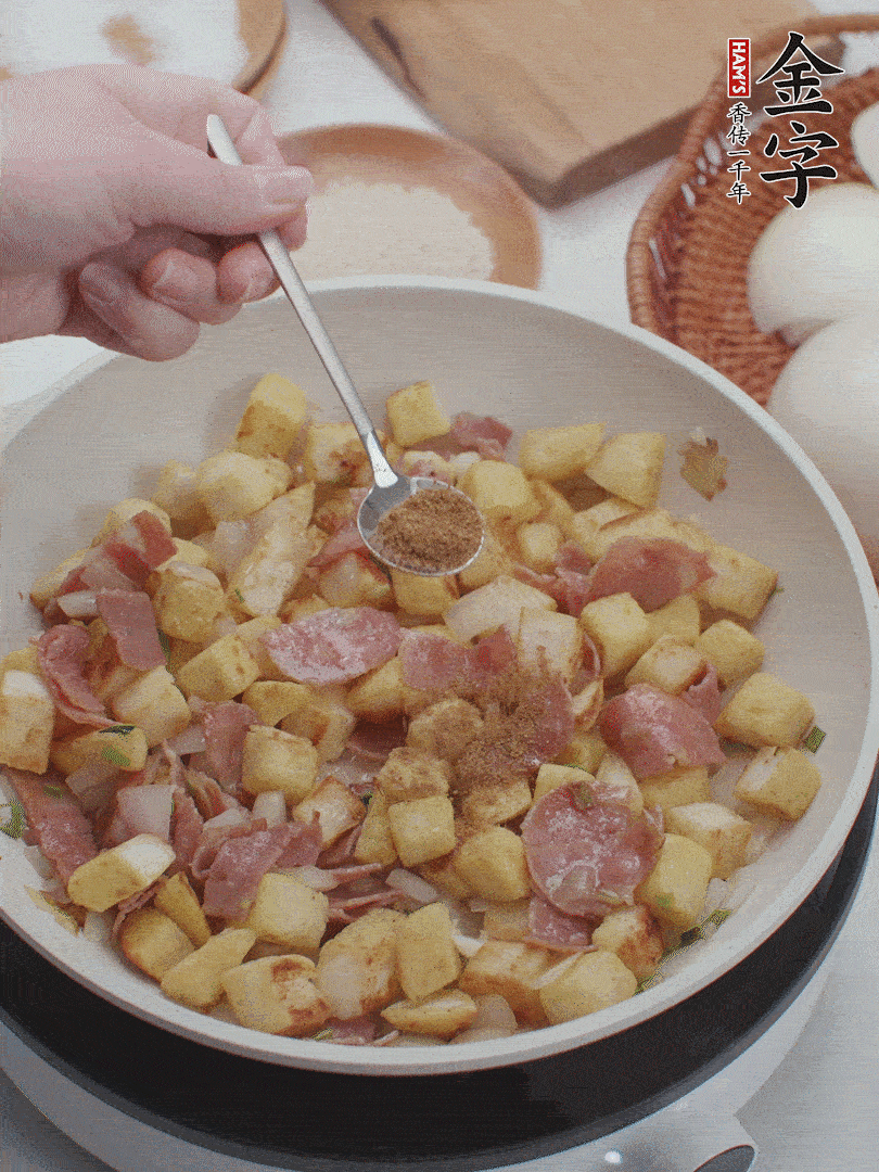 起鍋少油，煸香洋蔥丁、蔥白，加入金字培根火腿翻炒幾下，再加入饅頭丁、1小勺孜然粉、少許鹽翻炒均勻并鋪平。