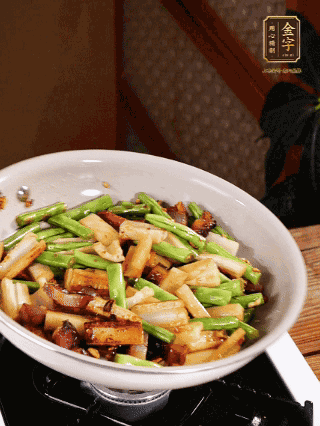油熱下蒜末、干辣椒、醬肉煸炒出香味，依次下藕條、豆角翻炒均勻